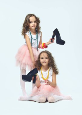 İki küçük kız annelerinin yüksek topuklu ayakkabılarıyla oynuyorlar. Poz verirler ve yetişkin olmaya çalışırlar. Stüdyo, White geri döner.