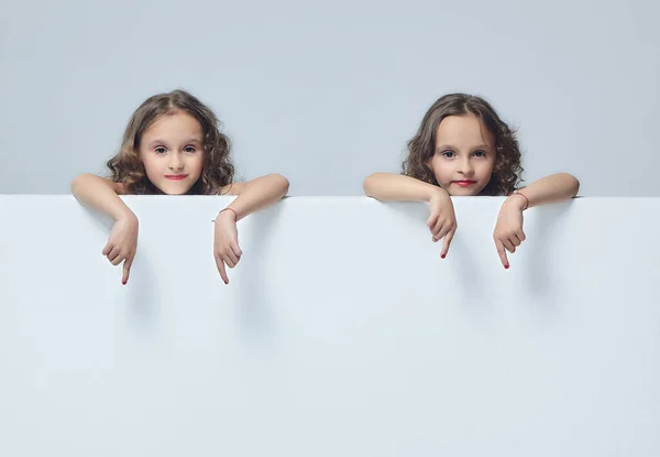 little girls point to an empty space. the concept of advertising. white back