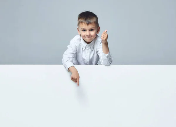 the little boy points to an empty space. thumbs up. white back
