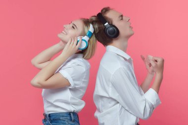 Kulaklıklı adam ve kız. Bir öpücükle duygularını ifade ederken müzik dinlemek. Pembe sırt