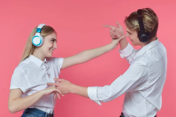 戴耳机的男人和女孩 在用亲吻来表达感情的同时听音乐 粉红背 — 图库照片