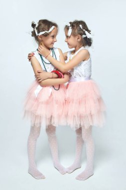 İki küçük kız annelerinin makyajıyla oynuyorlar. Poz verirler ve yetişkin olmaya çalışırlar. Stüdyo, beyaz sırt.