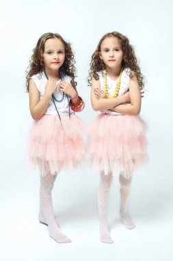 İki küçük kız annelerinin makyajıyla oynuyorlar. Poz verirler ve yetişkin olmaya çalışırlar. Stüdyo, beyaz sırt.