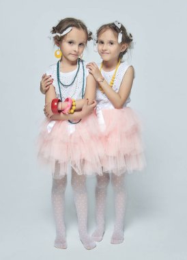 İki küçük kız annelerinin makyajıyla oynuyorlar. Poz verirler ve yetişkin olmaya çalışırlar. Stüdyo, beyaz sırt.