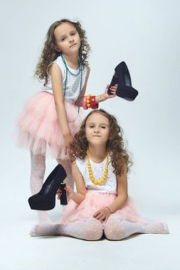 İki küçük kız annelerinin yüksek topuklu ayakkabılarıyla oynuyorlar. Poz verirler ve yetişkin olmaya çalışırlar. Stüdyo, White geri döner.