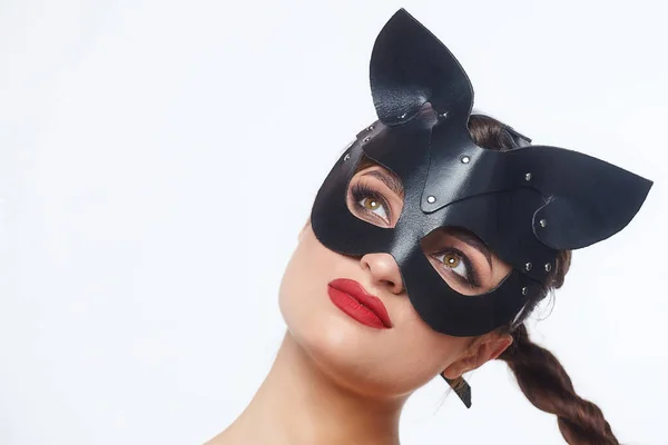 beautiful girl in a cat mask. playfully posing in front of the camera.