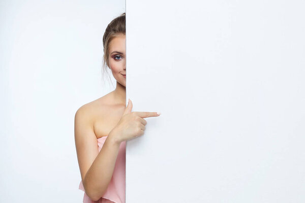 beautiful girl posing in front of the camera. he points to an empty space. advertising concept.