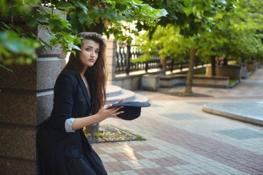 Yazın şapkalı güzel bir kızın portresi. Şehir parkındaki hippi bir kızın görüntüsü. Kız elinde bir şapka tutuyor ve sadaka istiyor.