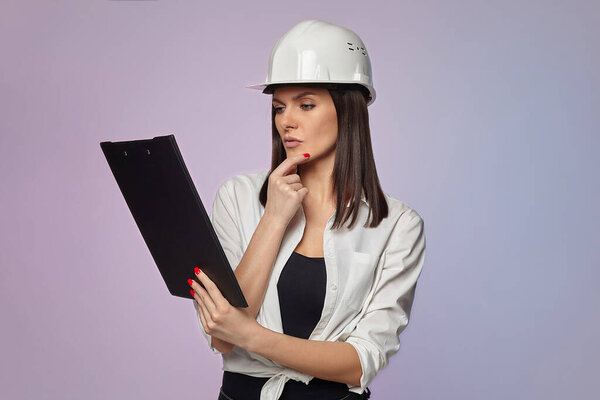 construction girl in a white helmet, holding a folder. the concept of a business woman who understands construction, repair and modernization..