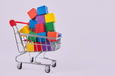 Reklam kavramı. Çok renkli küpleri olan bir alışveriş arabası. Bir çok alışverişi sembolize ediyor. İndirim ve satış konularında tasarımcının düzeni