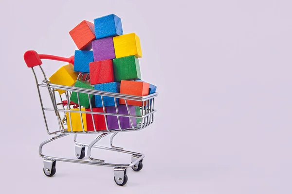 Reklam kavramı. Çok renkli küpleri olan bir alışveriş arabası. Bir çok alışverişi sembolize ediyor. İndirim ve satış konularında tasarımcının düzeni