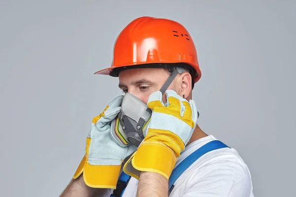 adult male in a construction helmet and a respirator. photo session in the Studio on a white background. concept of construction services