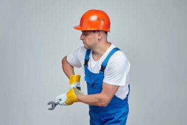 İnşaat kasklı yetişkin bir adam ingiliz anahtarıyla işini yapıyor. İnşaat hizmetleri kavramı