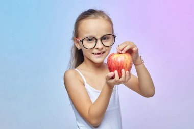 Gözlüklü küçük bir kız, elinde kırmızı bir elma.