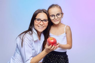 Anne ve kızı ellerinde büyük kırmızı bir elma tutuyorlar..