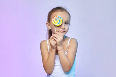 Küçük bir kız elinde büyük bir şeker tutuyor..