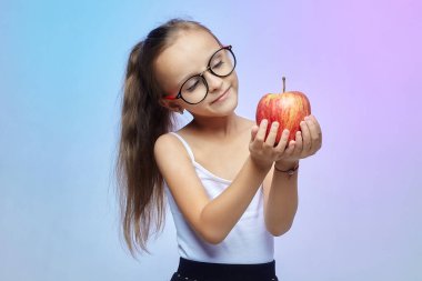 Gözlüklü küçük bir kız, elinde kırmızı bir elma.