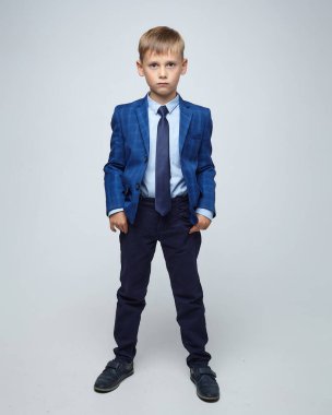 Ciddi bir suratı olan sarışın bir çocuk. Stüdyoda beyaz bir arkaplanda fotoğraf çekimi