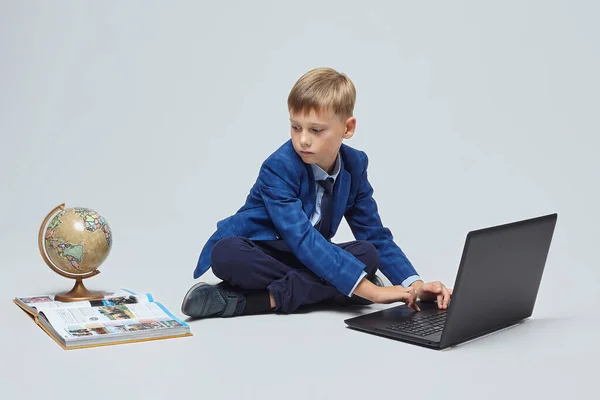 Biondo Ragazzo Abito Scolastico Seduto Fronte Computer Portatile Globo Libro — Foto Stock