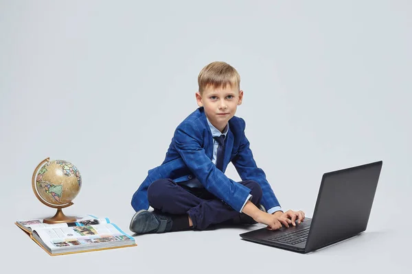 Biondo Ragazzo Abito Scolastico Seduto Fronte Computer Portatile Globo Libro — Foto Stock