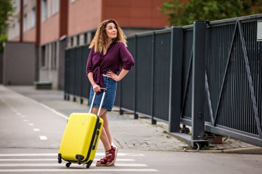 Sokakta bavullu bir kız. Bavullu kız tatile çıkıyor. Bavullu kız seyahat ediyor..