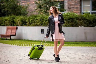 Sokakta bavullu bir kız. Bavullu kız tatile çıkıyor. Bavullu kız seyahat ediyor..