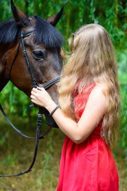 Atı olan güzel bir kadının açık hava portresi. Bir ağacın arka planına karşı.