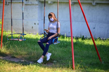 Gülümseyen genç manken güneşli bir bahçede salıncakta oturuyor..