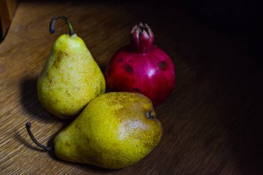 Bir çift taze olgun organik sarı armut ve ahşap masada bir nar. Seçici odak.