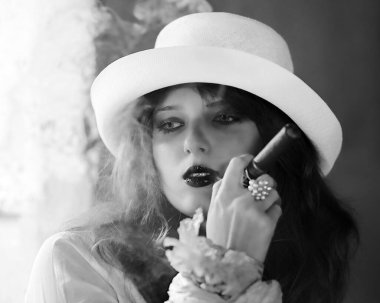 Elinde puroyla beyaz şapkalı genç bir kadının portresi. Modelin gözlerine odaklan. Purodan iç.