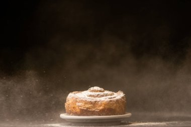 Siyah arka planda beyaz tabakta tatlı ekmek. 