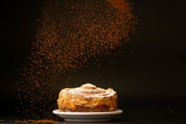 Siyah arka planda beyaz tabakta tatlı ekmek. 