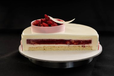 Siyah arka planda yarım ya da bir dilim kremalı pasta izole edilmiş.