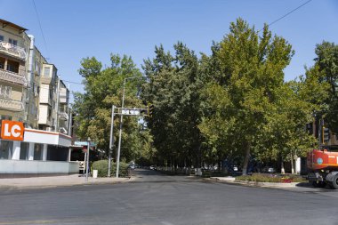 Şymkent, Kazakistan, 30 Ağustos 2025: Kavşakta giden arabalar, trafik ışıkları, apartmanlar ve açık mavi gökyüzü.