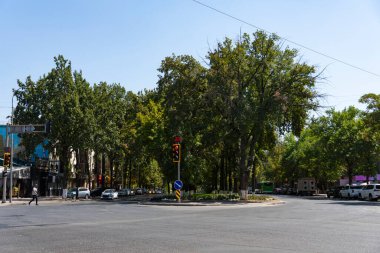 Şymkent, Kazakistan, 30 Ağustos 2025: Kavşakta giden arabalar, trafik ışıkları, apartmanlar ve açık mavi gökyüzü.