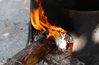 Ocağın içinde parlak turuncu alevlerle yanan odunlara yakın çekim. Sıcaklık, konfor ve kamp, yemek pişirme ve ısıtma kavramları için kırsal atmosfer