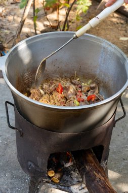 Bir kazanda yanan et, soğan, sarımsak ve dolma biber parçaları. Geleneksel açık hava yemek sahnesi, kırsal ve iştah açıcı.
