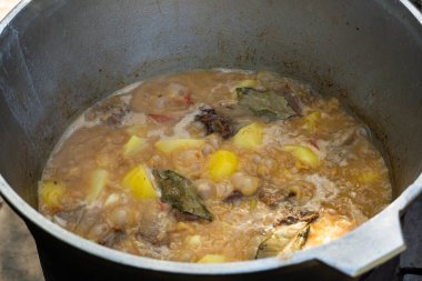 Bir kazanda yanan et, soğan, sarımsak ve dolma biber parçaları. Geleneksel açık hava yemek sahnesi, kırsal ve iştah açıcı.