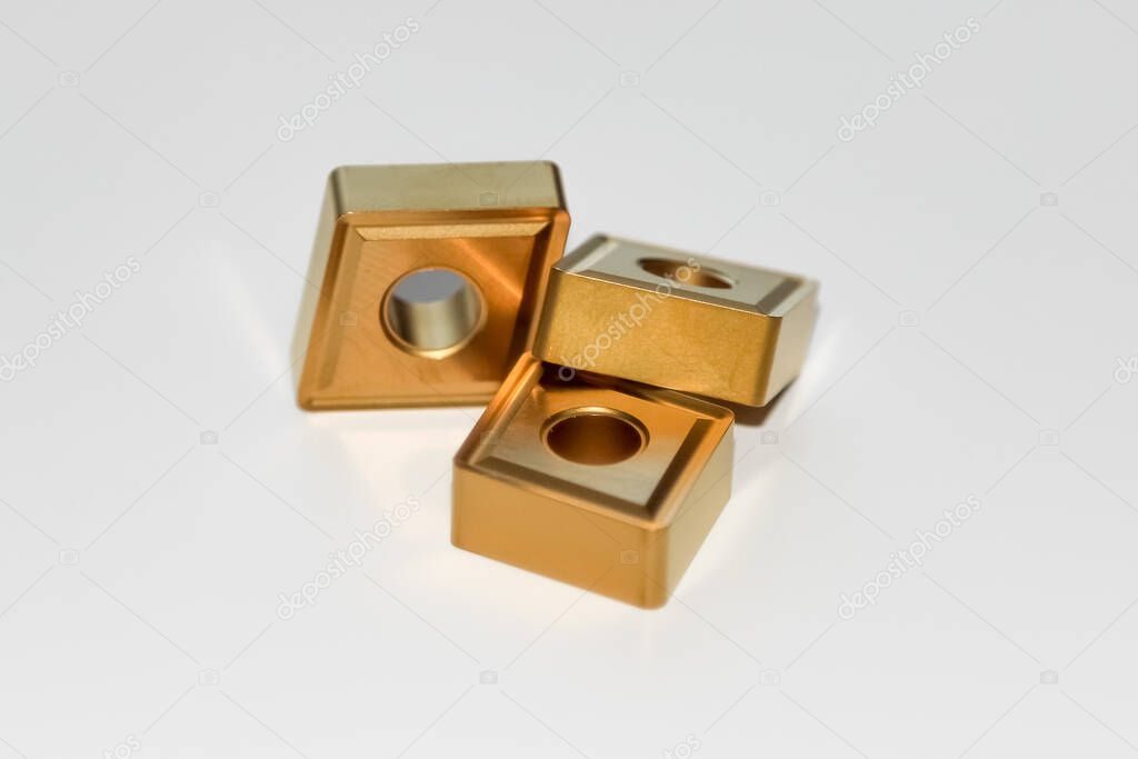 Three carbide inserts for CNC milling machine with selective focus isolated on white