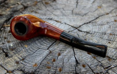 Çatlak bir ağaç kütüğünün üzerinde tüttüren bir pipoya yakın çekim