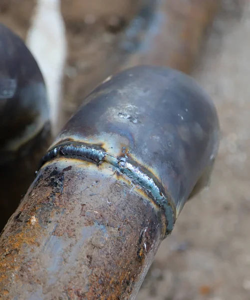 Closeup of a welded butt joint with some defects. Two rusty metal pipes welded together