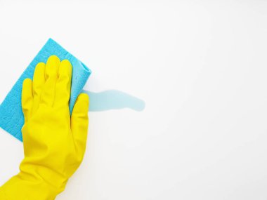 Mavi sıvıyı, beyaz arka planda sarı kauçuk eldivenli mavi bir süngerle temizlemek. Metin için boşluk.