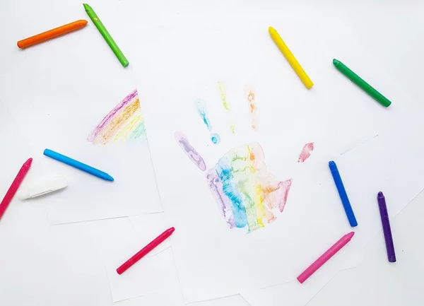 Lápis de cera coloridos. Uma impressão de mão em uma folha de papel branca . — Fotografia de Stock