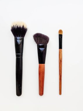 Ahşap kahverengi saplı kozmetik fırçalar ve beyaz arka planda kahverengi iplik..