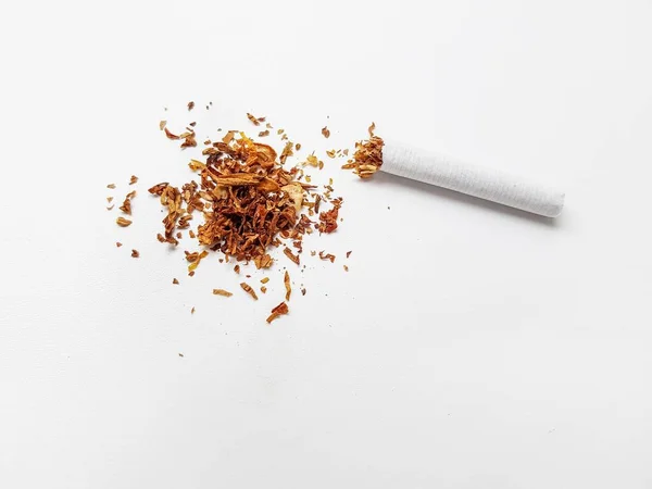A broken cigarette and a pile of tobacco leaves on a white background. — Stock Photo, Image