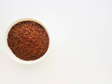 Beyaz zemin üzerinde beyaz seramik bir tabakta keten tohumları.