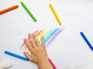 Beyaz kağıda renkli mum boya kalemleri. Çocuklar tarafından çizilmiş bir gökkuşağı..