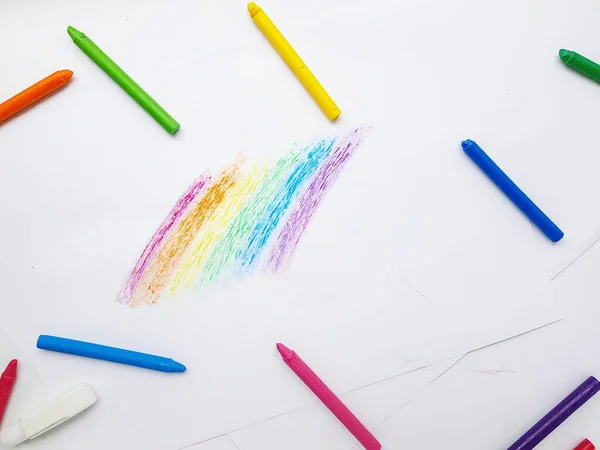 Lápices de cera de colores sobre papel blanco. Un arco iris dibujado por manos de niños . —  Fotos de Stock