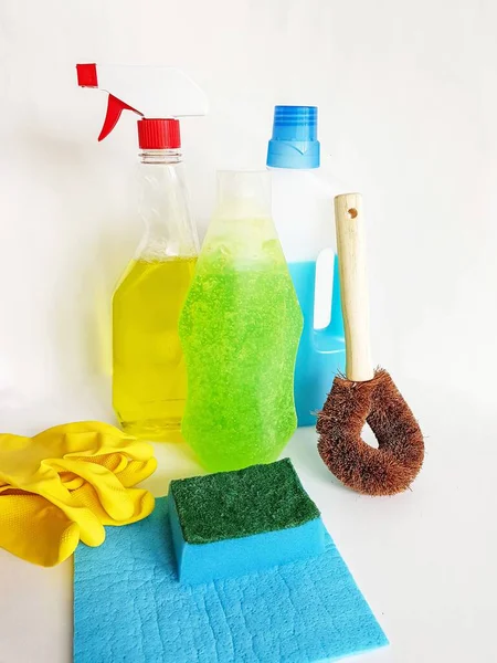 Cleaning products, yellow rubber gloves, blue sponge and rag, liquids in bottles, spray on a white background. — Stock Photo, Image