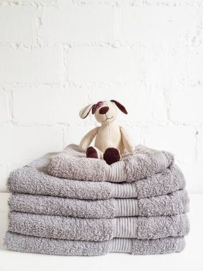 Beyaz tuğla bir duvara karşı pelüş, beyaz bir oyuncakla dolu bir yığın temiz havlu..